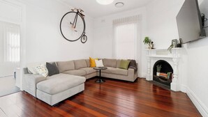Una sala de estar con un sofá, una mesa redonda, una chimenea y una bicicleta colgada en la pared.