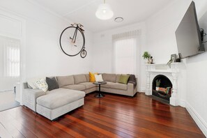 A living room with a sofa, a round coffee table, a fireplace, and a bicycle hanging on the wall. - Heart of Northbridge | Food, Bars & Culture (Northbridge)
