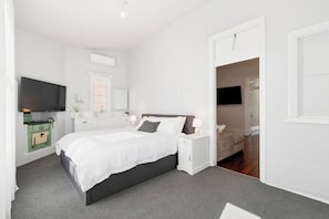 A modern bedroom with a large bed, bedside tables, a TV, and a green vintage-style stove. - Heart of Northbridge | Food, Bars & Culture (Northbridge)