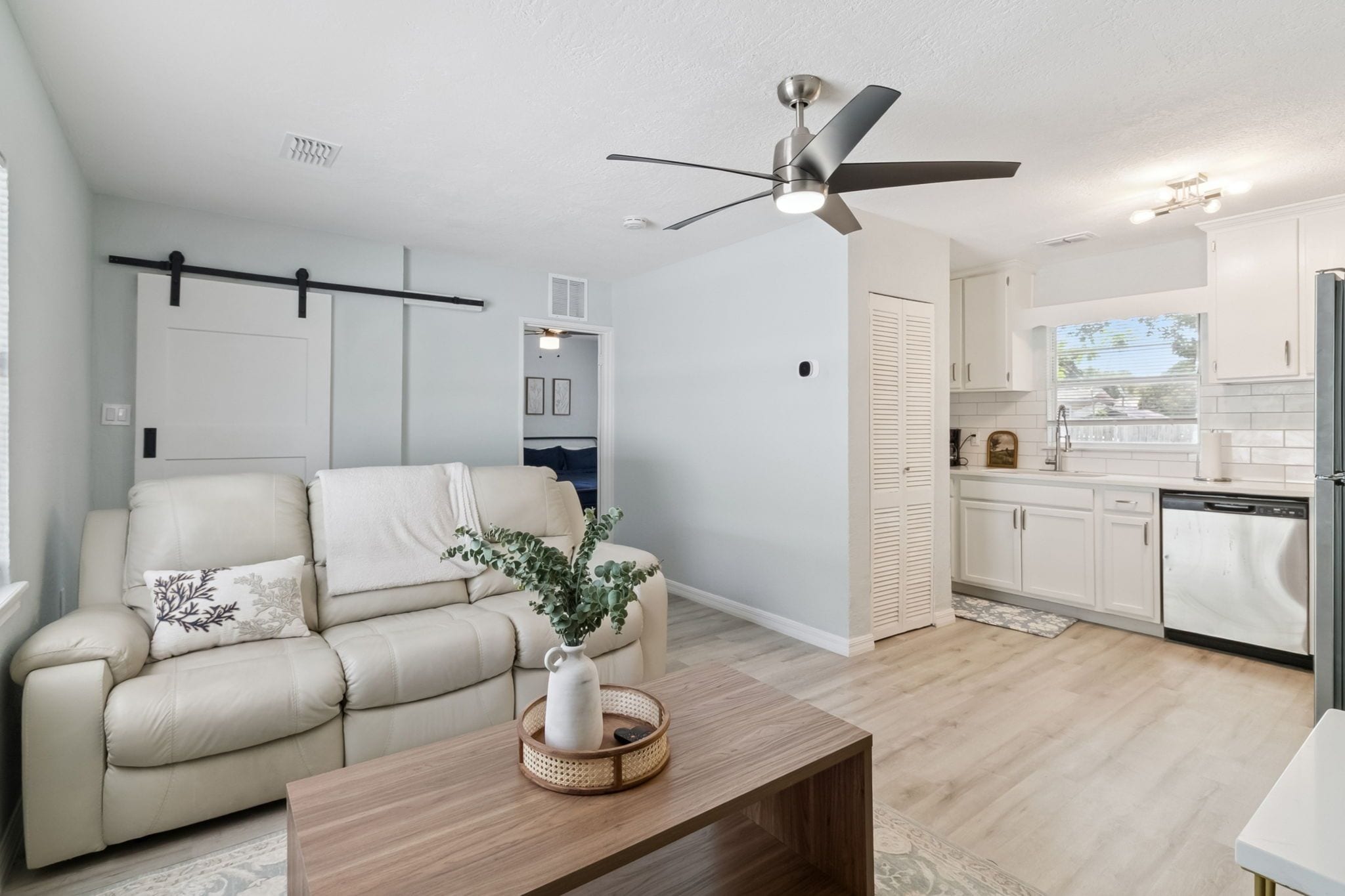 Un salon moderne avec un canapé, une table basse et un ventilateur de plafond.