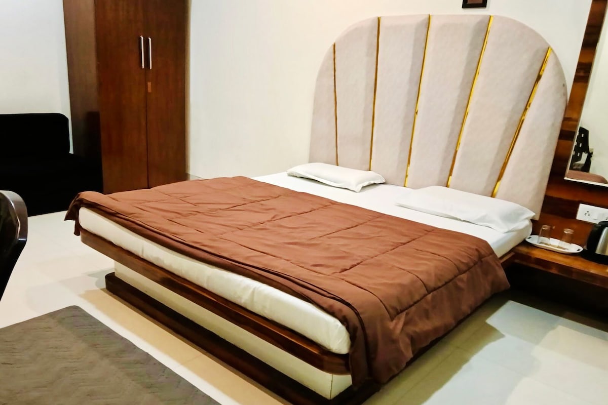 A bed with a brown bedspread, a white pillow, and a headboard with vertical lines.