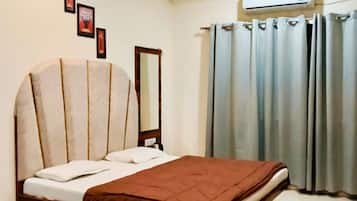 Un dormitorio con una cama, ventilador de techo, aire acondicionado y cortinas.