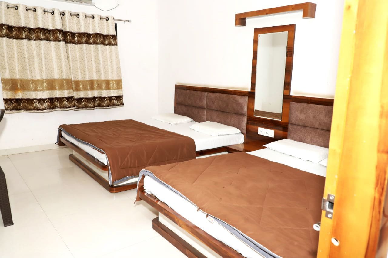 Habitación de hotel con dos camas, un espejo y una cortina.