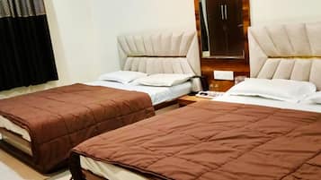 A hotel room with two beds, a large mirror, and a window with curtains.