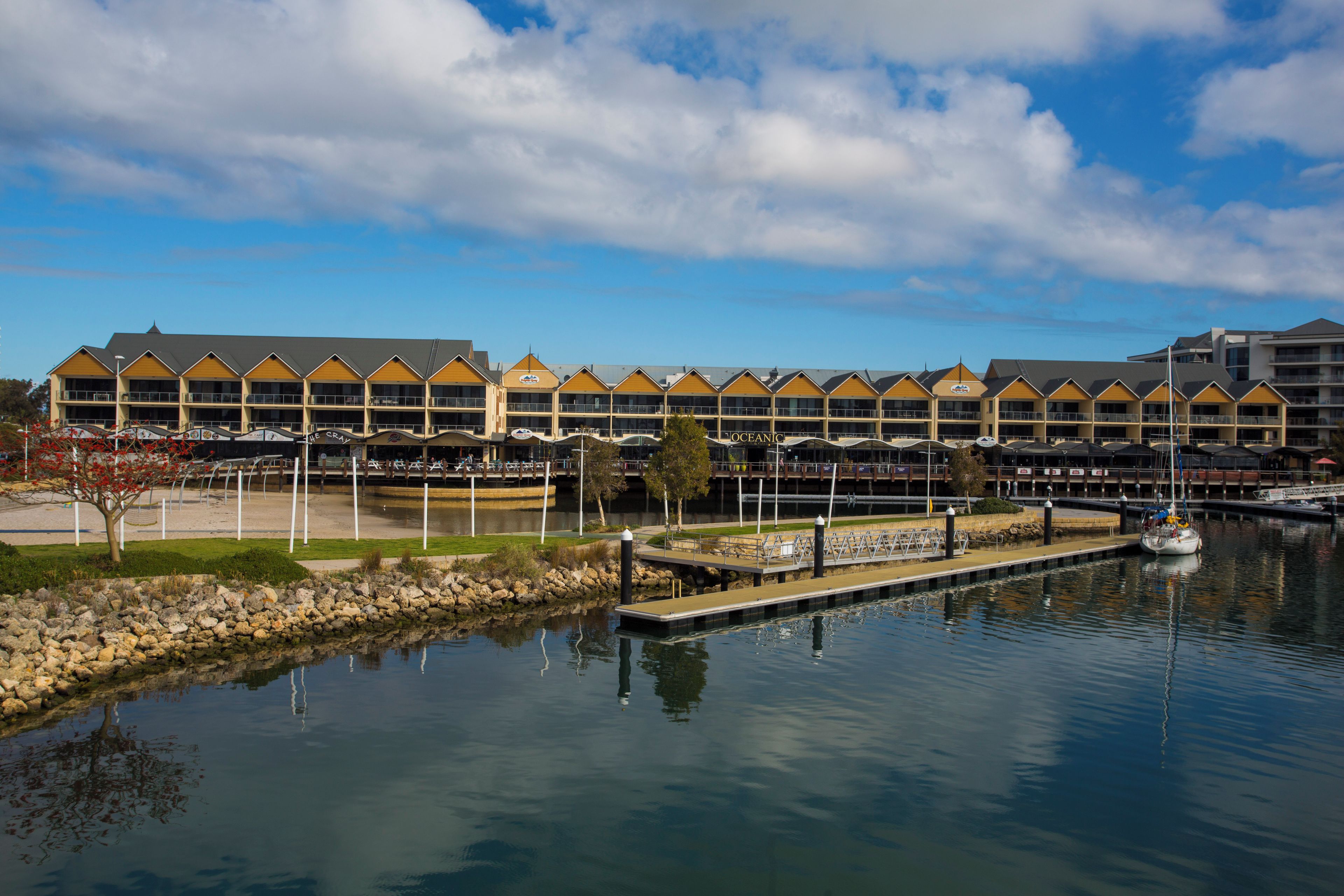 A waterfront hotel with multiple balconies, a marina, and a calm lake.