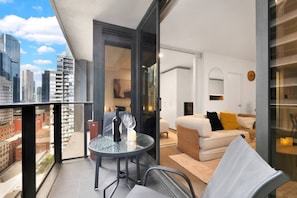 Eine moderne Wohnung mit Balkon, einem Essbereich und einem Wohnzimmer mit Sofa und Kissen.