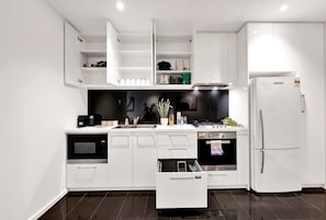 A modern kitchen with white cabinetry, a built-in oven, a microwave, and a refrigerator. - L27 2BR 2Bath | Free Parking, Pool, Gym| Sth Cross (Melbourne)
