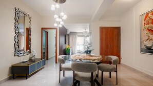 Uma área de refeições moderna com mesa de vidro, cadeiras acolchoadas e um objeto decorativo central.