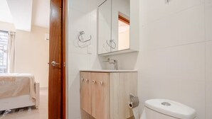 Casa de banho com sanita, lavatório e espelho.