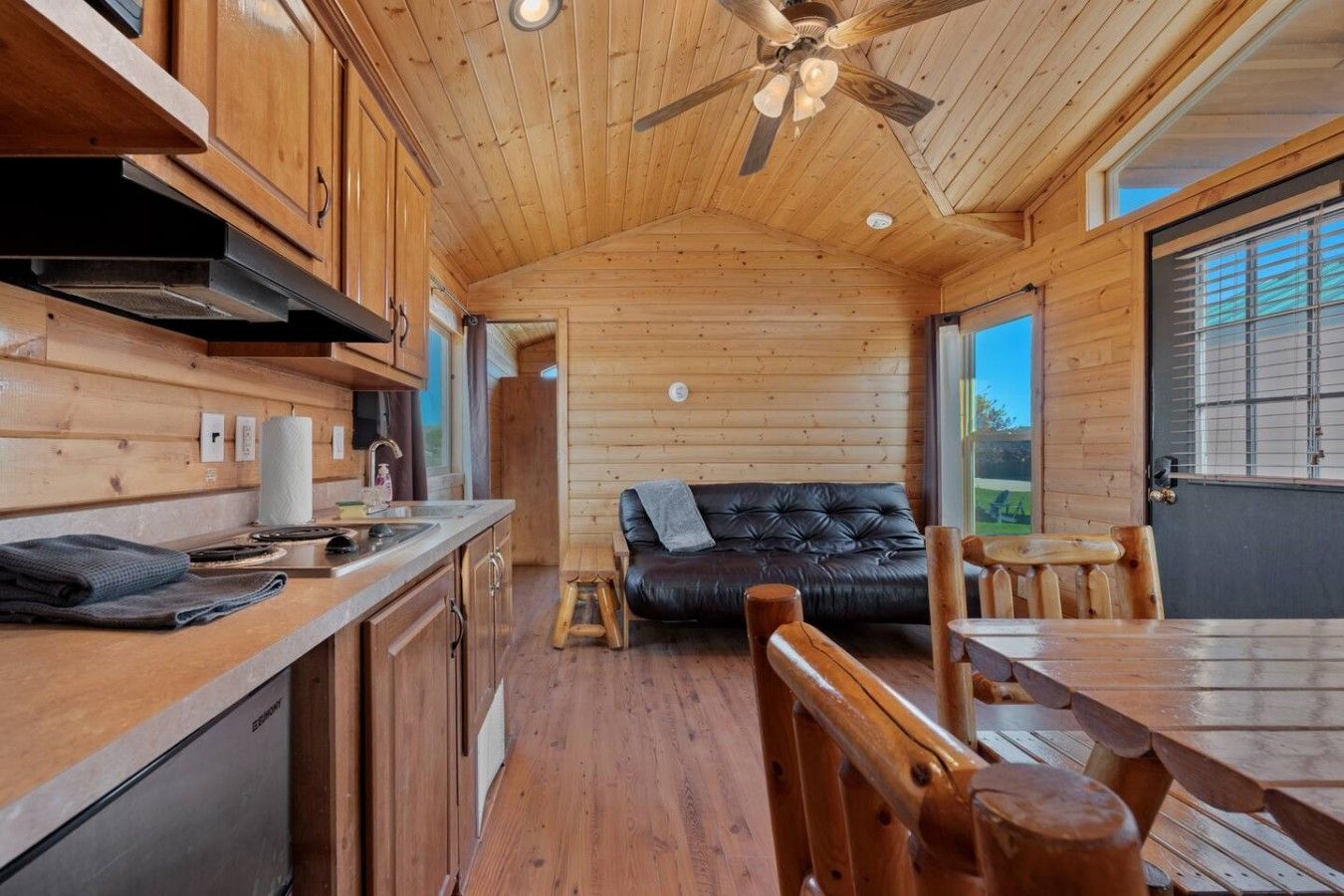 Una cabaña compacta con kitchenette, un sofá y zona de comedor.