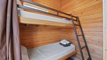 Een stapelbed met een ladder, houten wanden en een raam.