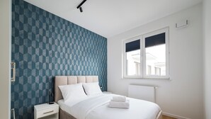 Een slaapkamer met een bed, nachtkastje en een raam.