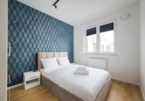 Une chambre à coucher avec un lit, une table de chevet et une fenêtre.