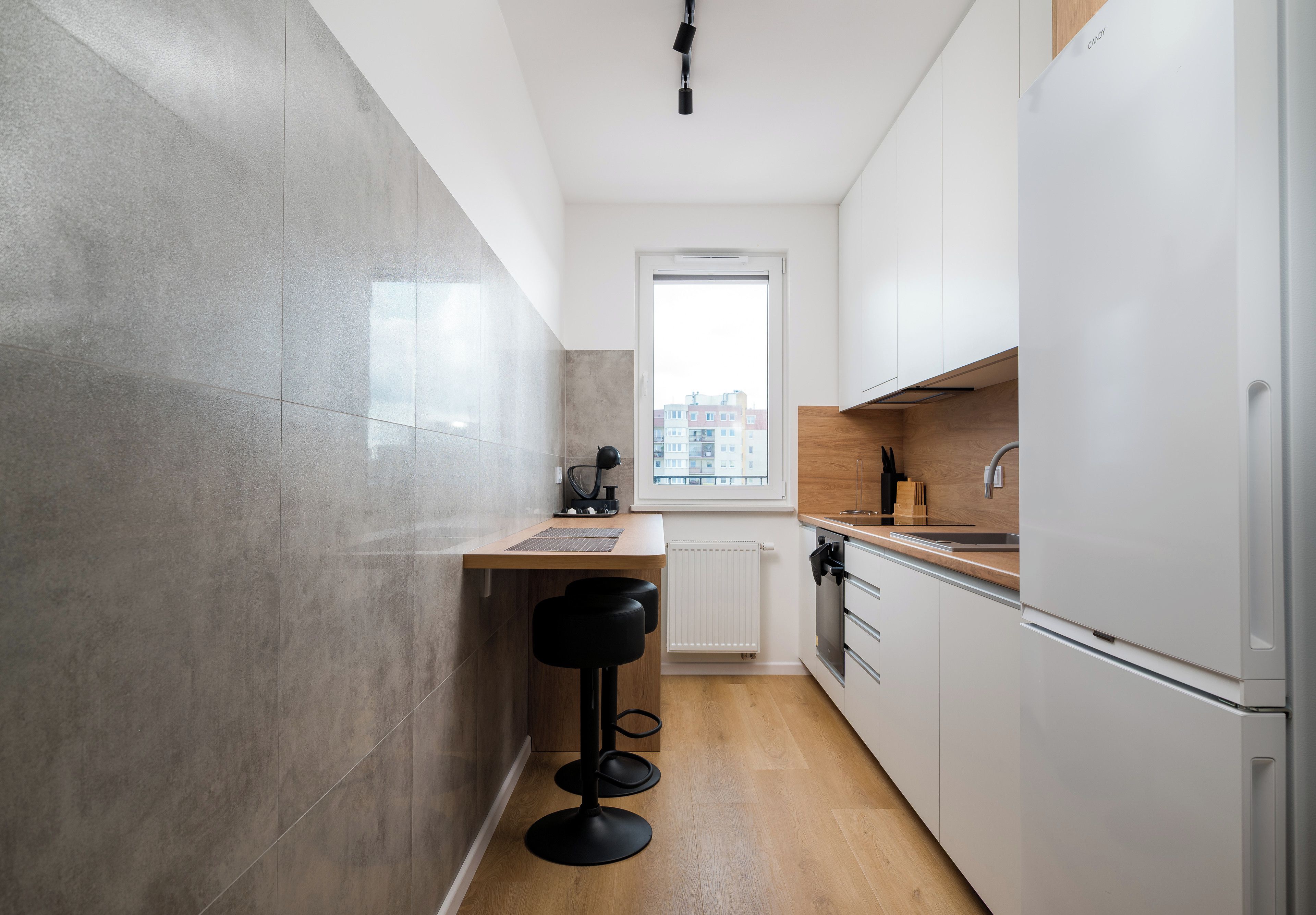 A modern kitchen with a wooden countertop, a built-in oven, and a white refrigerator.