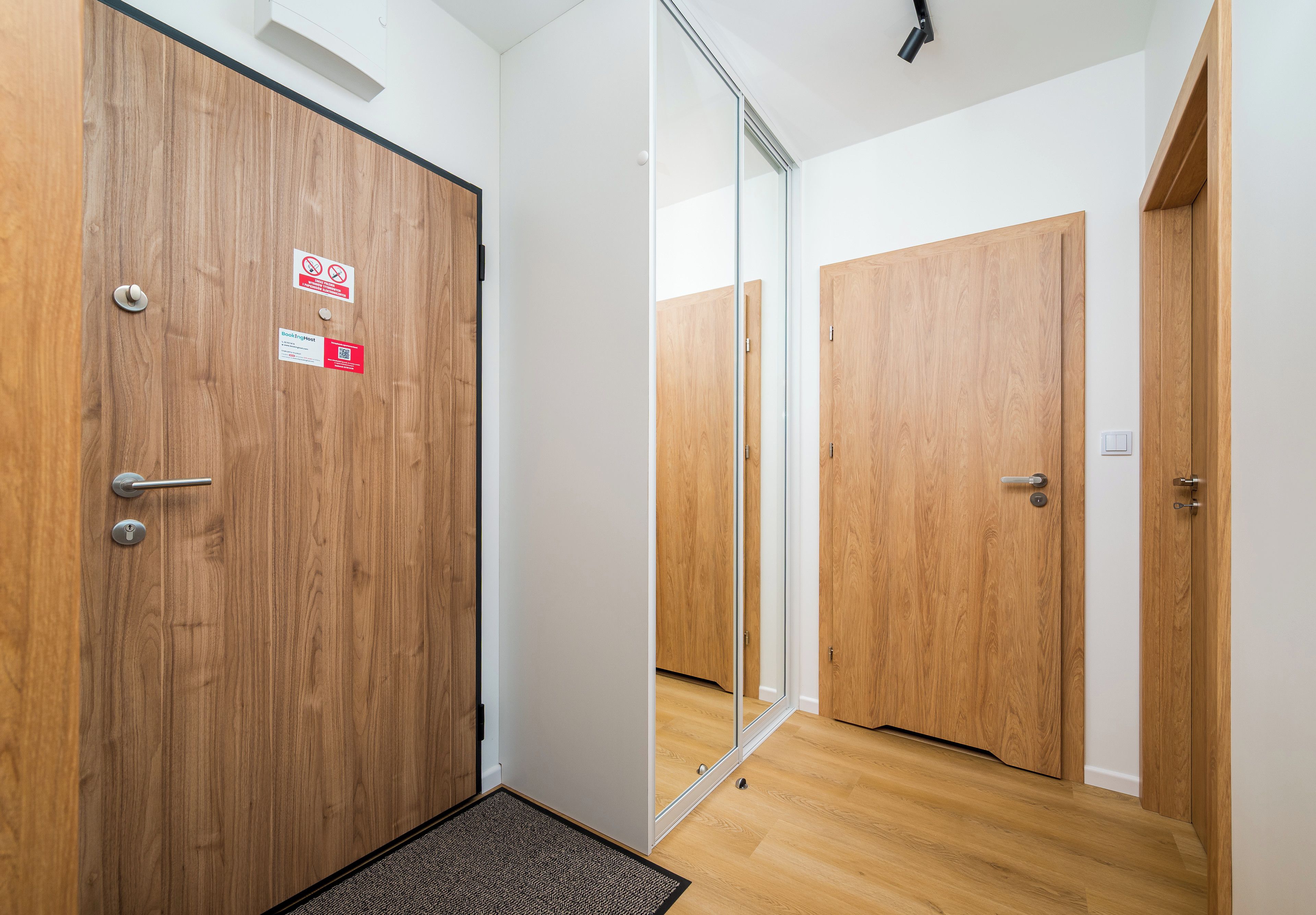 Een hotelkamer met houten deuren, een spiegel en een deurmat.