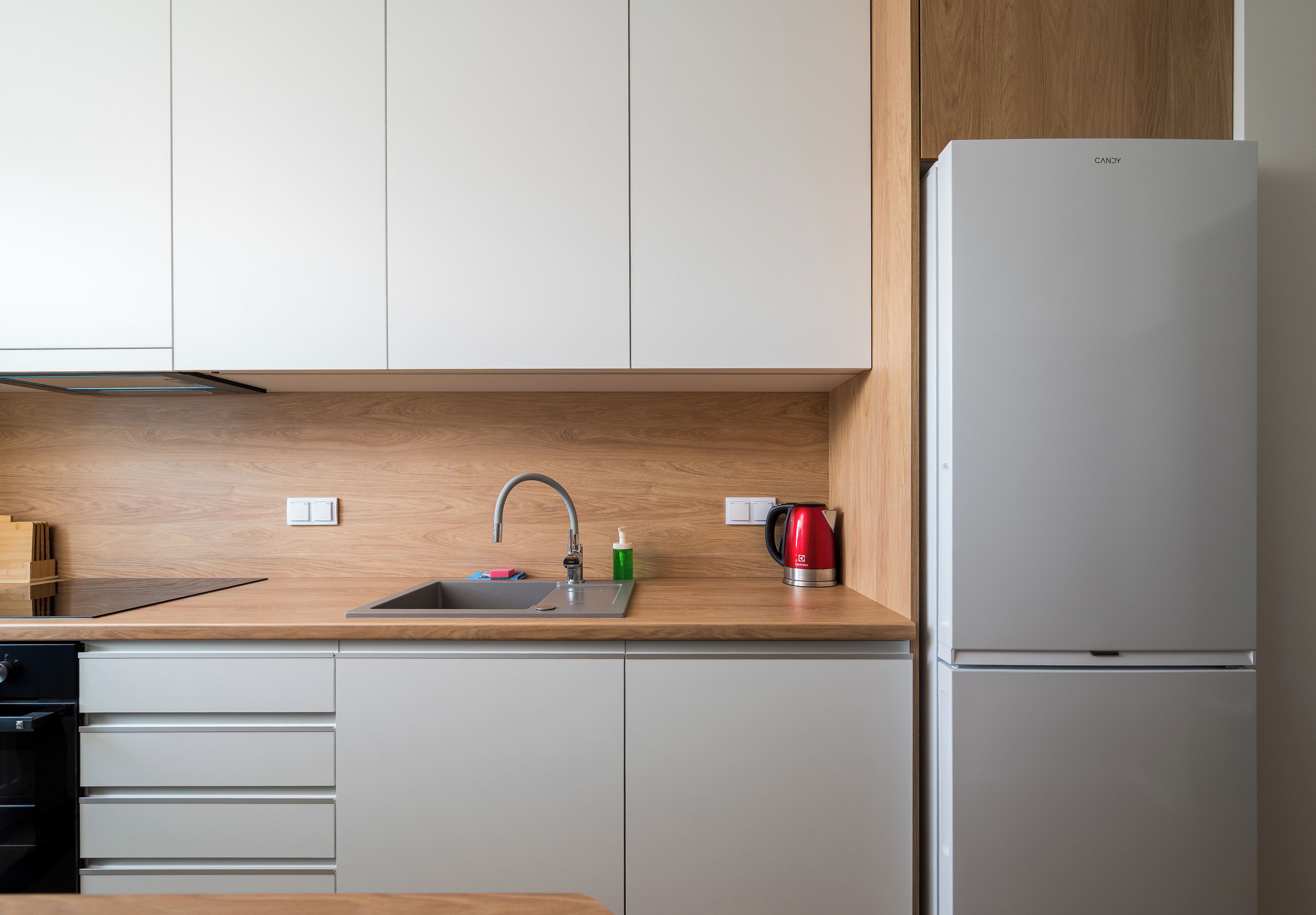 Een moderne keuken met een inbouwspoelbak, een roestvrijstalen koelkast en houten keukenkastjes.