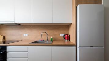 Een moderne keuken met een inbouwspoelbak, een roestvrijstalen koelkast en houten keukenkastjes.