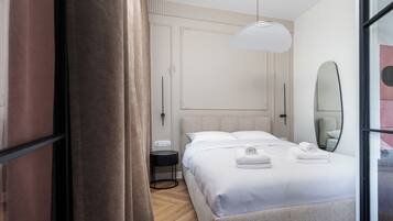 Une chambre d’hôtel moderne avec un grand lit, une table de chevet, un miroir et un luminaire suspendu.
