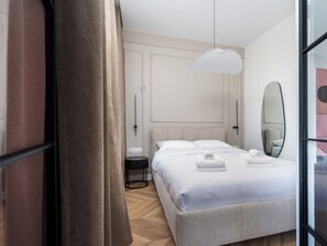 A modern hotel room with a large bed, a bedside table, a mirror, and a hanging light fixture. - Narutowicza 45 Signature Apartment (Łódź)