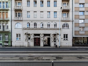 A multi-story building with classical architectural features, including a central entrance with a dark-colored door and a series of statues above it. - Narutowicza 45 Signature Apartment (Łódź)