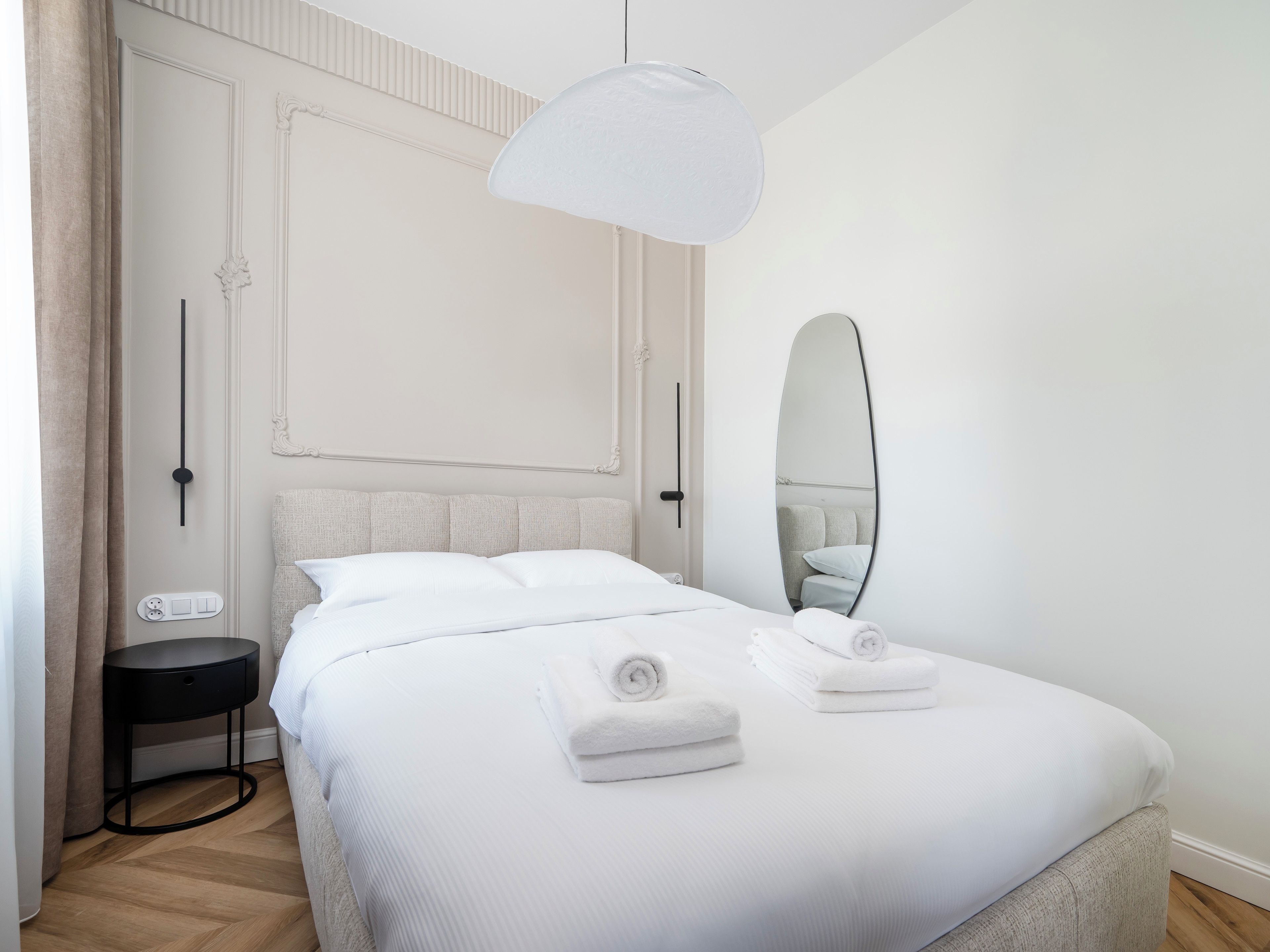 Une chambre d’hôtel avec un lit, une table de chevet et un grand miroir.