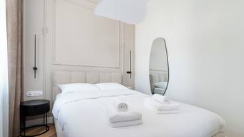 Une chambre d’hôtel avec un lit, une table de chevet et un grand miroir.
