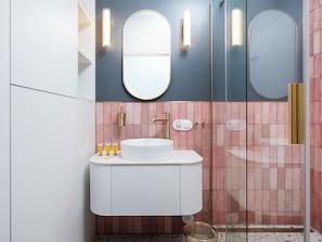 A modern bathroom with a white sink, pink tiled walls, and a glass shower enclosure. - Narutowicza 45 Signature Apartment (Łódź)