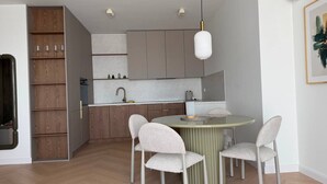 Une cuisine moderne avec une table de salle à manger ronde, deux chaises et un luminaire suspendu.