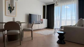 Una sala de estar moderna con un sofá, sillas, un televisor y un comedor.