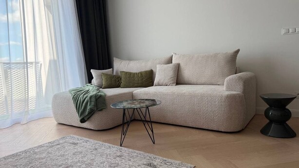 Un salon avec un canapé, une petite table ronde et un tapis à motifs.
