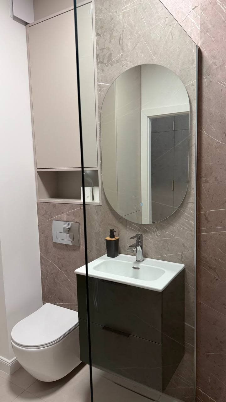 Ein modernes Badezimmer mit Toilette, Waschbecken und Spiegel.