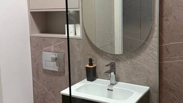 Ein modernes Badezimmer mit Toilette, Waschbecken und Spiegel.