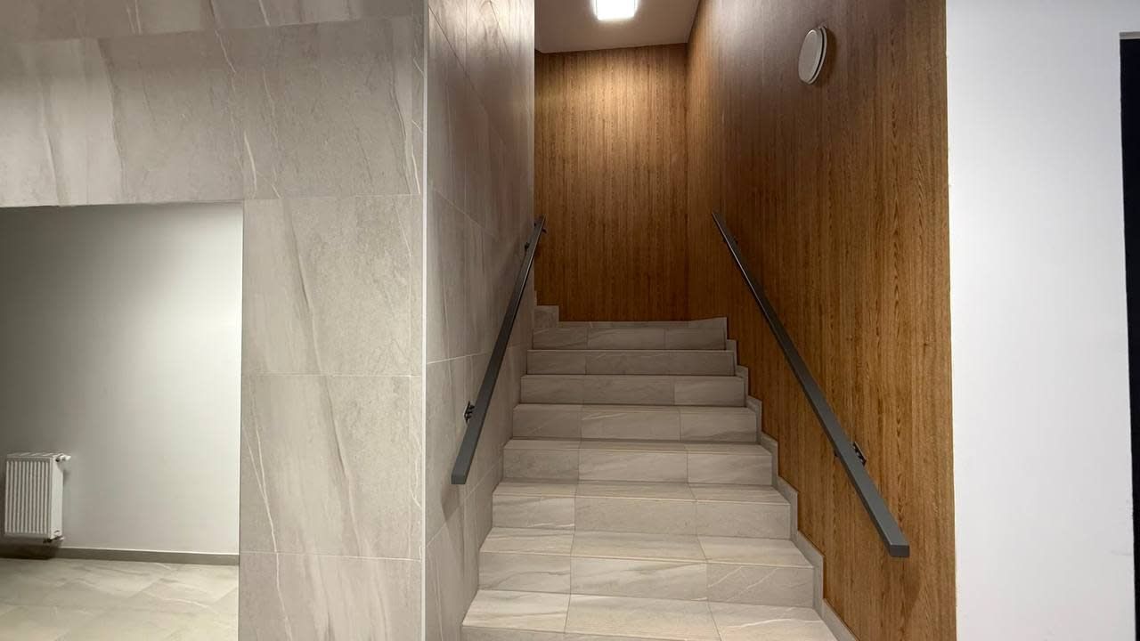 Eine Holzwand mit einer Metallhandläufe versehenen Treppe, die zu einer oberen Etage führt.