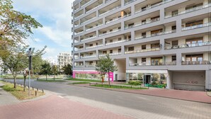 Een meerlaags woongebouw met balkons, een voetpad en een winkel met reclameborden.
