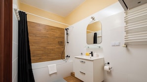 Een badkamer met een houten wand, een witte wastafel, een spiegel, een douche en een toilet.