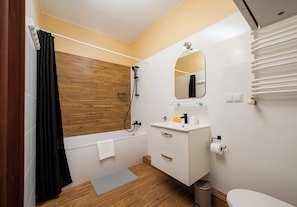 Une salle de bain avec un mur en bois, un lavabo blanc, un miroir, une douche et des toilettes.