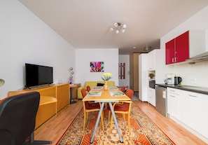 Un espace de vie compact comprenant un coin repas, une kitchenette et un téléviseur.