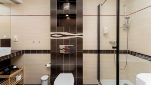 Un baño moderno con ducha, inodoro y tocador con espejo.