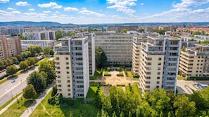 Ein Hochhaus mit mehreren Balkonen, einem Innenhof und umliegender Bepflanzung.