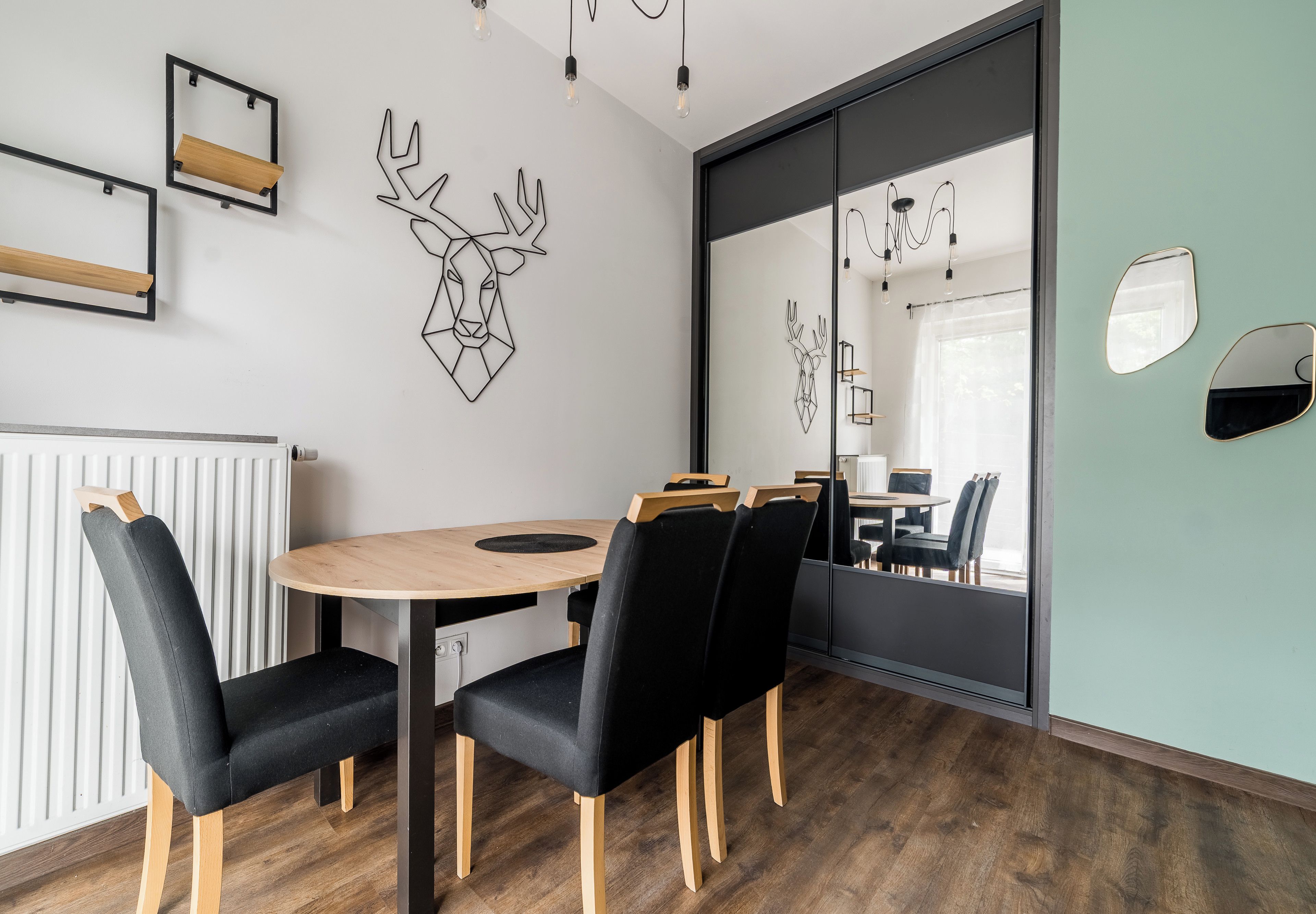 A modern meeting room with a round table, black chairs, and a wooden floor.