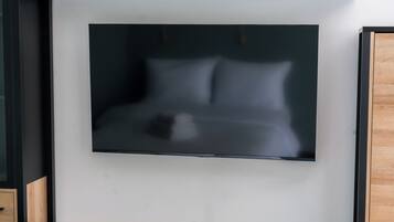 Une photo encadrée représentant un lit avec des oreillers, accrochée à un mur. Un meuble en bois se trouve à gauche.