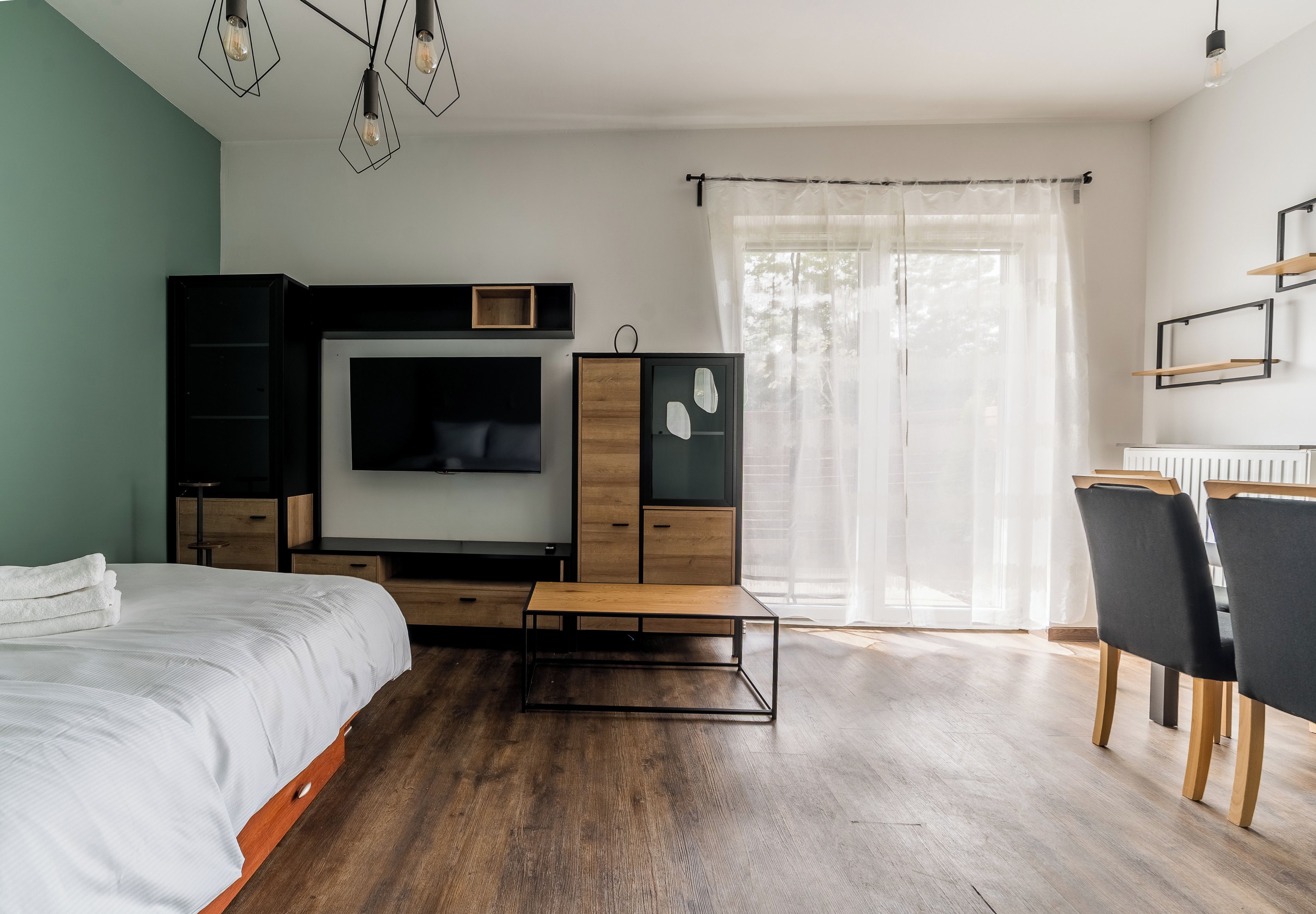 A modern bedroom with a bed, a TV, a desk, and a chair.