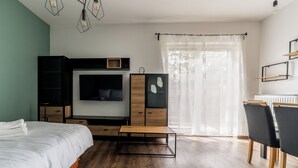 Een moderne slaapkamer met een bed, een televisie, een bureau en een stoel.