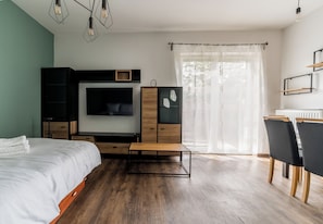 Un dormitorio moderno con cama, televisor, escritorio y silla.
