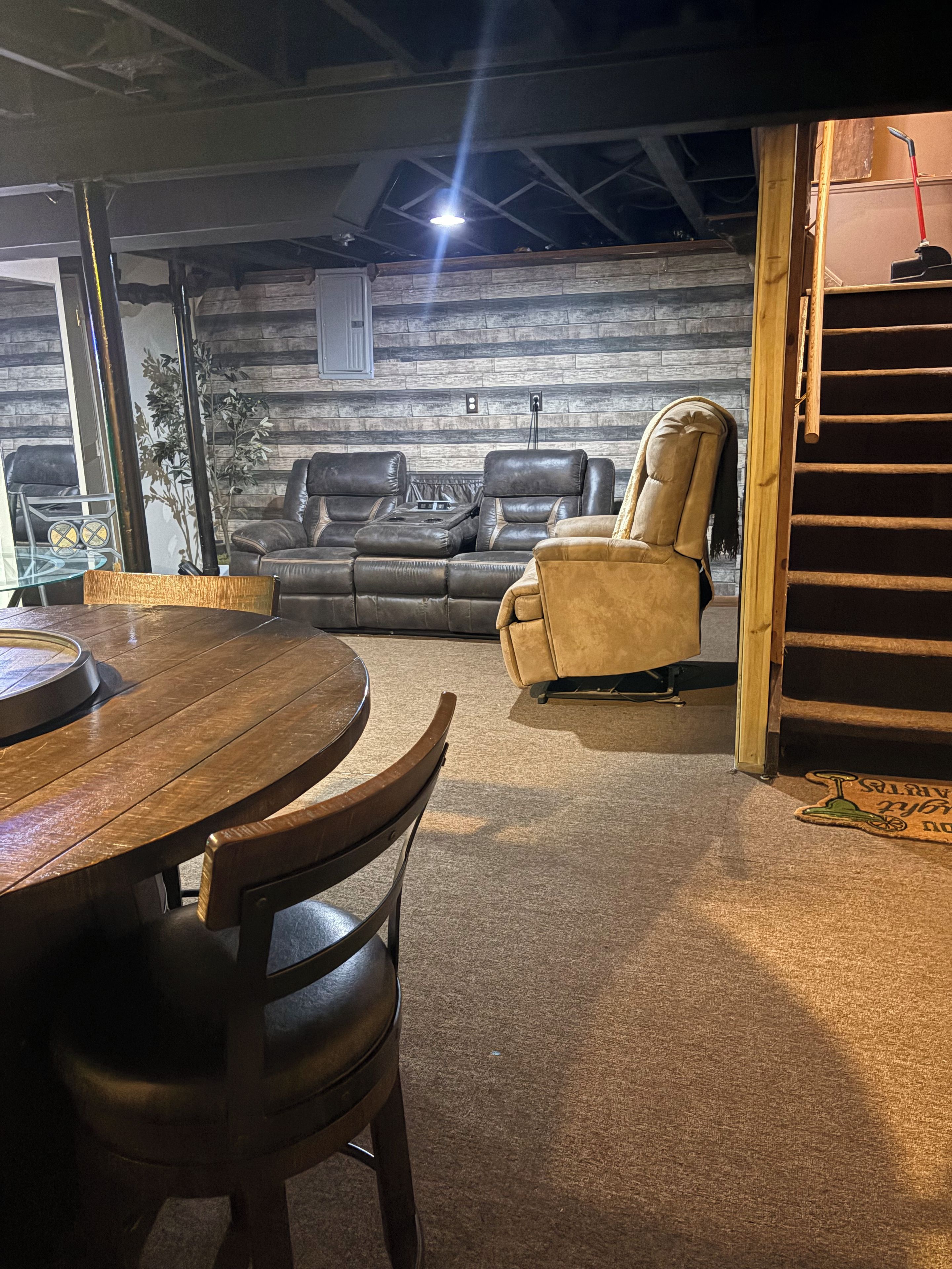 Une pièce avec une table à manger en bois, deux canapés en cuir et un sol recouvert d’une moquette.