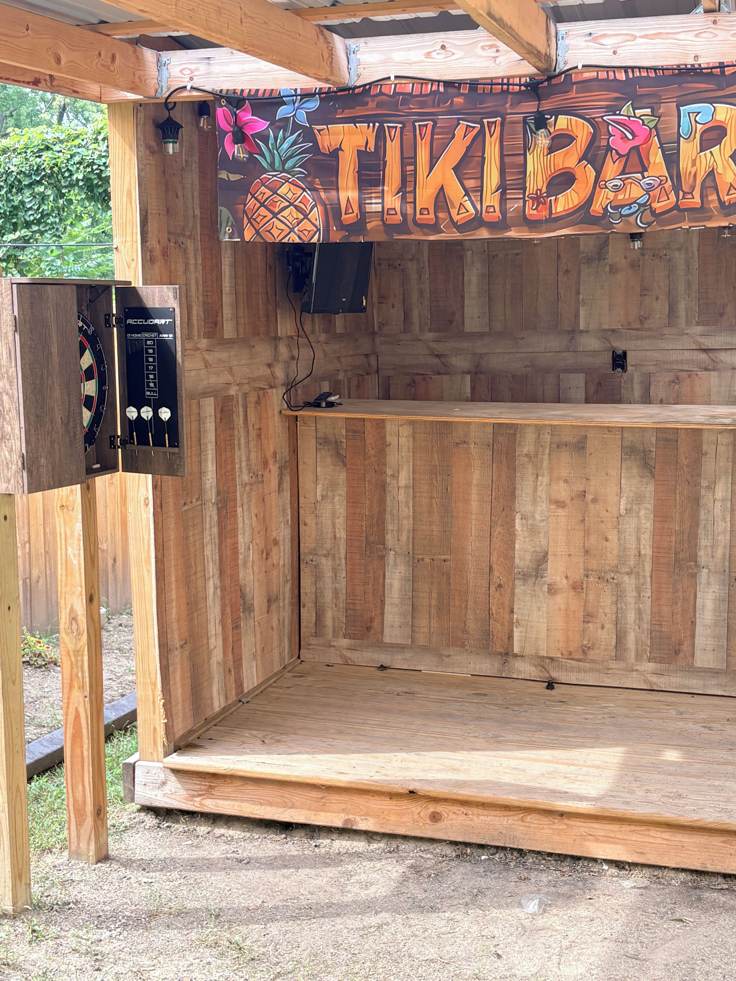 Um bar de tiki de madeira com um alvo de dardos e um jukebox.
