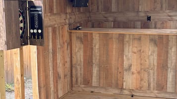 Um bar de tiki de madeira com um alvo de dardos e um jukebox.