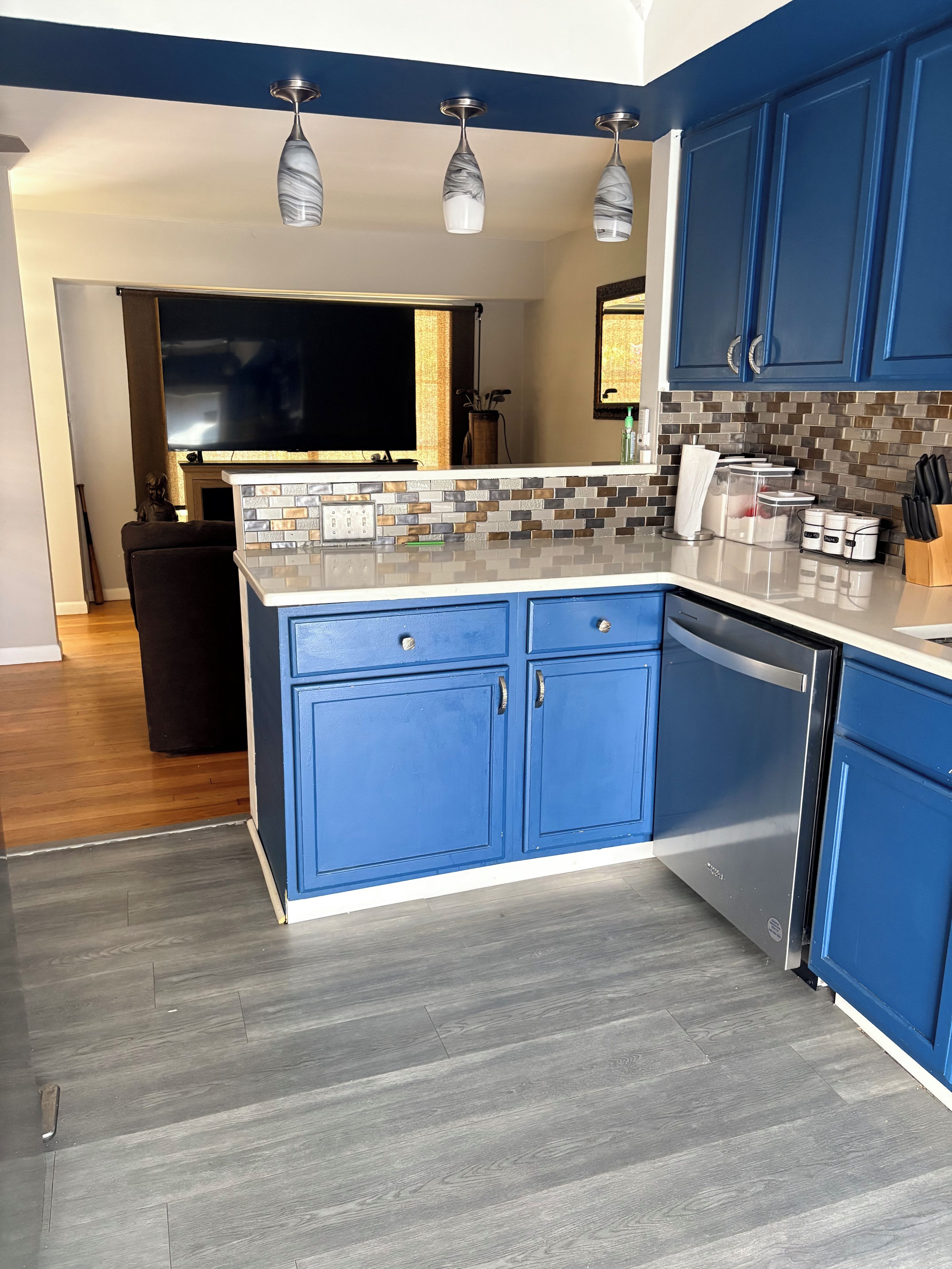 Cozinha moderna com armários azuis, painel de azulejos e máquina de lavar louça embutida.