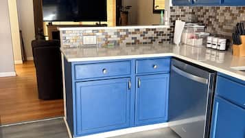 Cozinha moderna com armários azuis, painel de azulejos e máquina de lavar louça embutida.