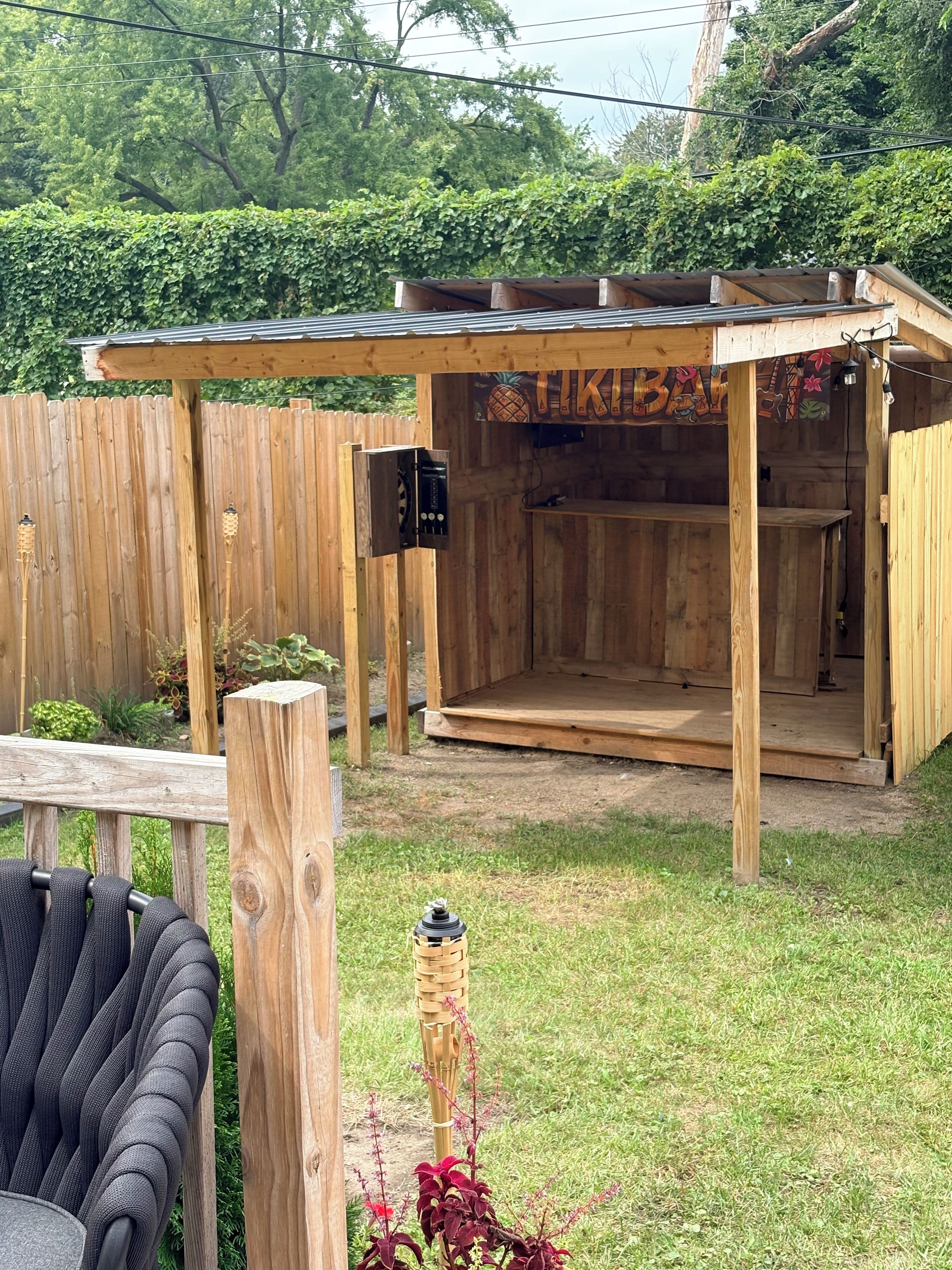 A wooden outdoor structure with a covered seating area and a barbecue grill.